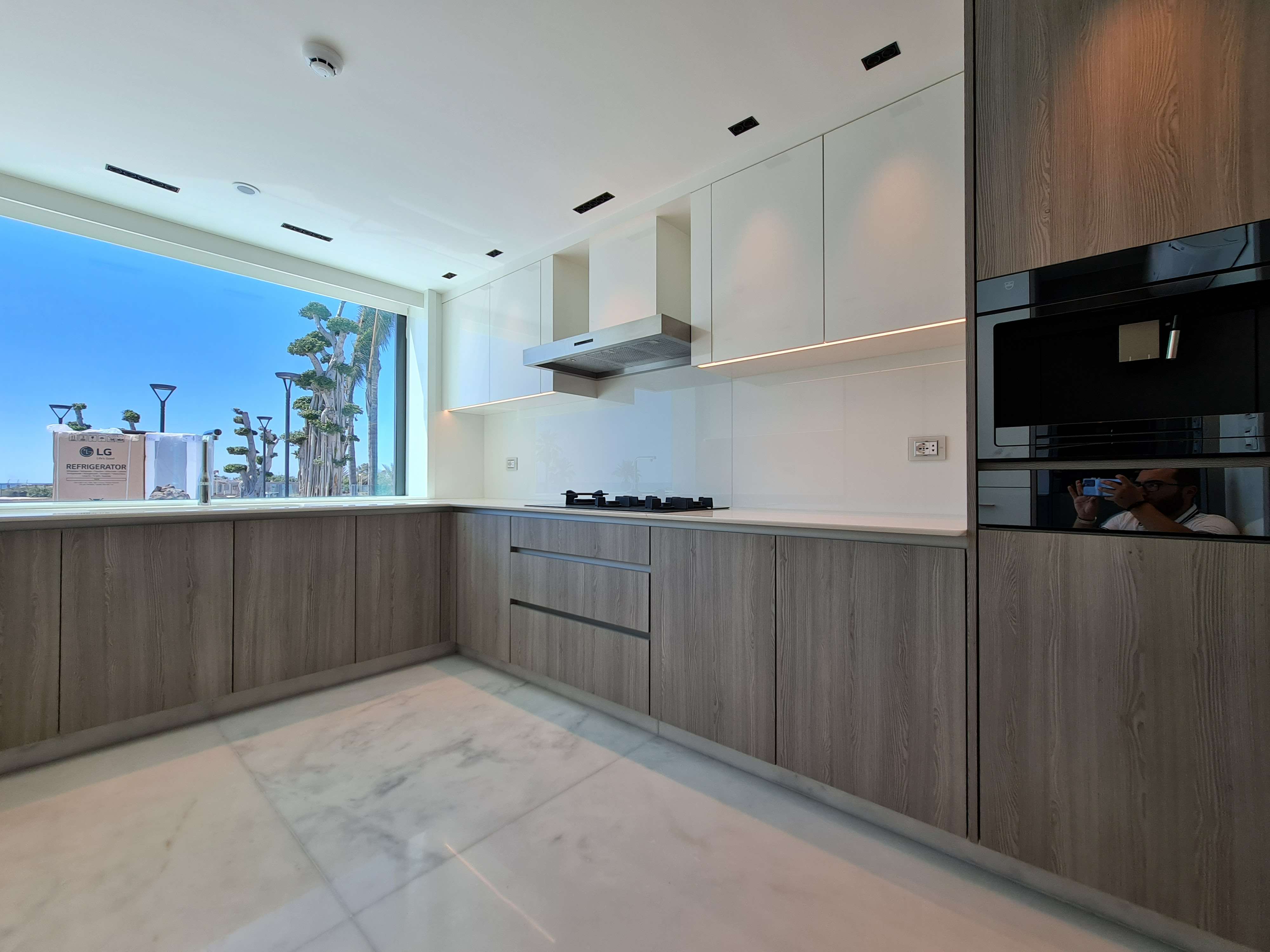 Bright and airy kitchen with natural wood tones and large windows by La Fabriqua